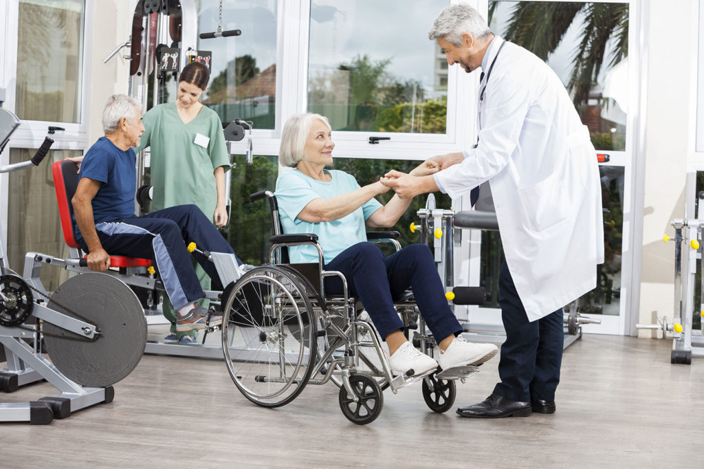 Photo of Doctor Holding Senior Woman's Hands In Wheelchair
