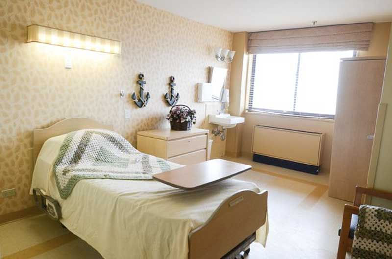 A cozy, well-lit hospital room featuring a comfortable bed, soft lighting, and thoughtful decor, designed to create a warm and inviting atmosphere for patients.